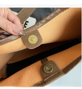 Detail of brown leather tote bag with dual gold magnetic closures and soft lining