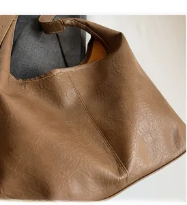 Detail of soft brown pleated PU leather shoulder bag with smooth orange lining