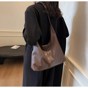 Detail of a large dark brown faux leather shoulder bag with vintage texture on a model