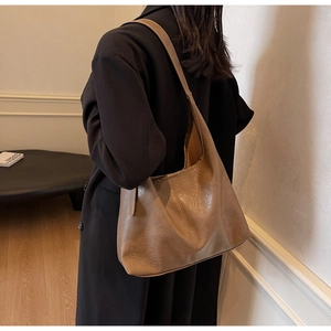 Close-up of retro brown textured leather tote bag worn with a black wool coat