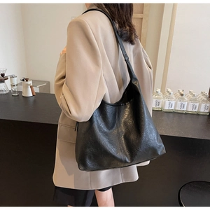 Woman wearing large black tote bag with retro wrinkled texture in a cozy cafe setting