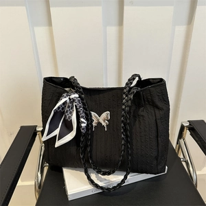 Grand sac cabas plissé noir avec boucle papillon en métal et foulard sur une chaise