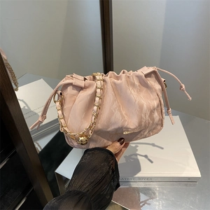 Light pink pleated bucket bag with gold chain strap and drawstring closure