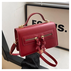 Detail einer burgunderroten Ledertasche mit vertikalen Reißverschlüssen und langen Zuglaschen