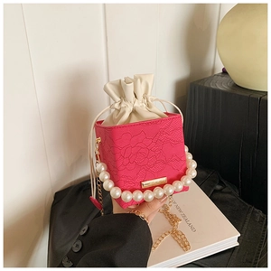 Close-up of pink box bag with 3D floral lace texture and chunky white pearl handle