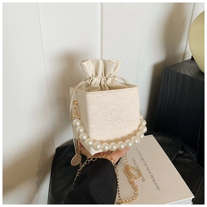 Detail der cremefarbenen Spitzenbeuteltasche mit Perlenperlengriff und Goldkette