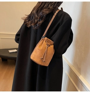 Borsa a secchiello in camoscio caramello con coulisse indossata da una modella