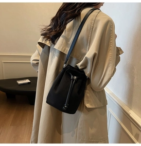 Dettaglio della borsa a secchiello nera con coulisse indossata da una modella