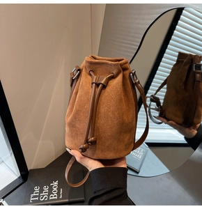 Detail view of a vintage brown suede bucket bag featuring a classic drawstring closure