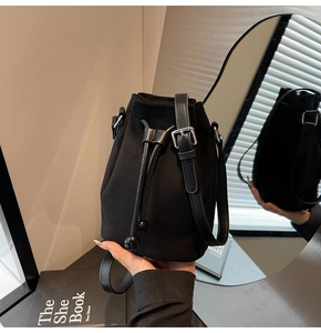 Macro view of matte black bucket bag with drawstring closure and adjustable leather strap