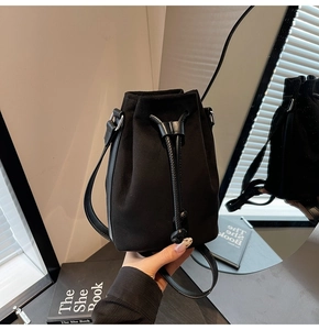 Detail of black suede drawstring bucket bag with mirror reflection in a vintage setting