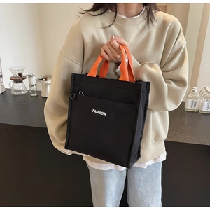 Close-up of contrast orange handles and black waterproof oxford fabric tote bag