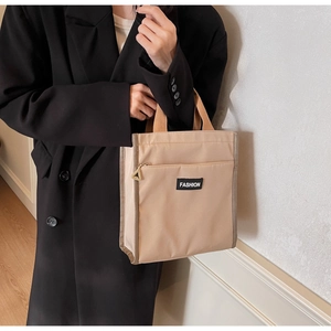 Detail of minimalist nylon handbag featuring a front zipper pocket and Fashion label