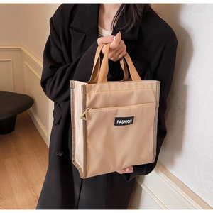 Close-up of beige nylon tote bag featuring front zipper pocket and Fashion label