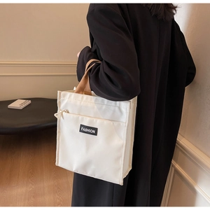 Detail of white waterproof oxford tote bag featuring a front zipper pocket and tan handles