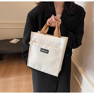 Close-up of cream waterproof oxford tote bag with brown woven handle and fashion label