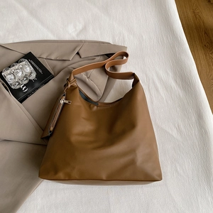 Detail view of large brown faux leather tote bag with matching small zipper pouch