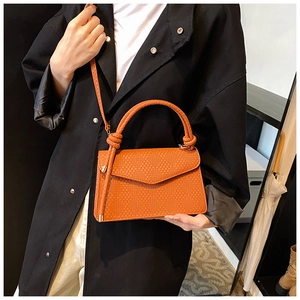 Détail du sac bandoulière marron-orange avec texture tissée et poignée