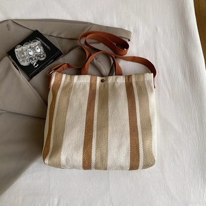Détail du sac cabas en toile rayée avec lanières marron et fermeture par bouton-pression