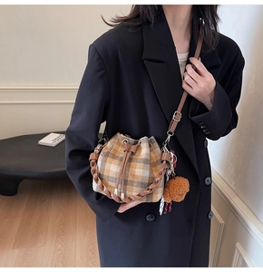 Sac seau en laine à carreaux avec poignée tressée et breloque ours sur un modèle