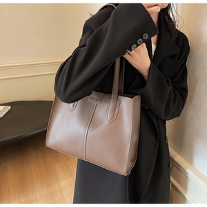 Detail of dark brown tote bag with FASHION embossing on minimalist PU leather texture