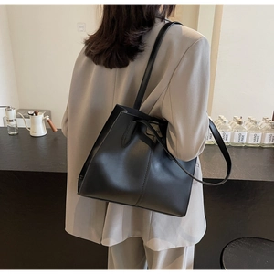 Detail of matte black tote bag with vertical stitching and Fashion brand plate