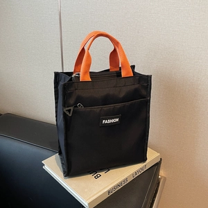 Large black waterproof oxford tote bag with orange handles and front zipper pocket