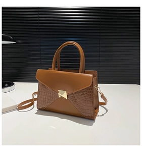 Close-up of caramel leather handbag featuring mixed textures and a gold square clasp