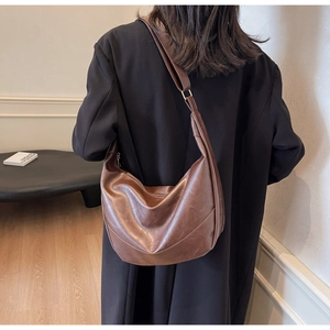 Detail of vintage brown crescent tote bag featuring soft PU leather texture and wide strap