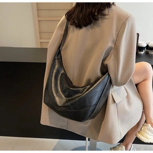 Side view of large black crescent shoulder bag on beige blazer for commute style