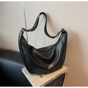 Macro shot of black crescent hobo bag with grainy texture and golden metal hardware details