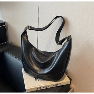 Detail of black pebbled leather crescent bag featuring golden buckle and adjustable strap