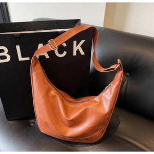 Detail of caramel brown PU leather slouchy bag with adjustable golden buckle and wide strap
