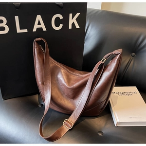 Detailed view of the brown retro crescent bag with PU leather texture on a sofa