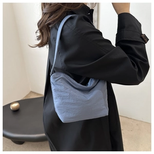 Light blue hobo shoulder bag styled with a black trench coat for daily commute fashion