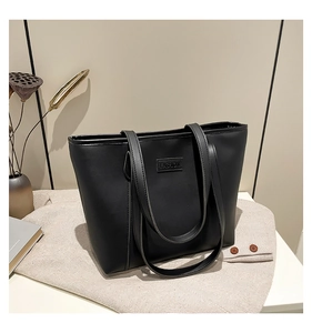 Close-up of black leather tote bag with FASHION embossed detail and dual straps