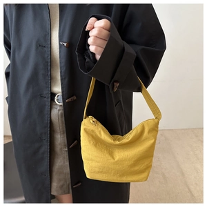 Detail of a bright yellow canvas underarm bag showing the hobo shape and smooth zipper closure