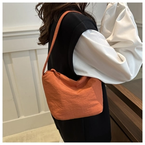 Vue détaillée du sac hobo plissé orange vif en toile porté par un mannequin de côté