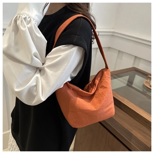 Vue détaillée du sac à épaule en nylon orange avec une forme de dumpling minimaliste
