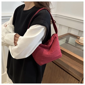 Gros plan d'un sac porté épaule bordeaux en toile montrant la texture et la bandoulière