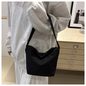 Vue détaillée du sac d'épaule noir en nylon avec fermeture éclair dans un décor de style