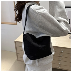 Vue de côté d'un sac fourre-tout noir en nylon porté par un mannequin pour le style