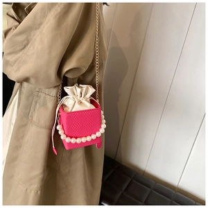 Pink quilted leather bucket bag with white satin drawstring and elegant pearl chain
