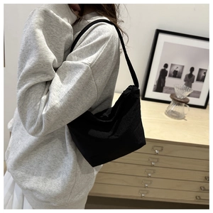Sac à bandoulière minimaliste en toile noire porté par un mannequin dans un intérieur
