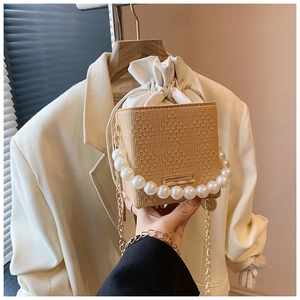 Detail of woven straw bucket bag featuring pearl handle and secure drawstring inner pouch
