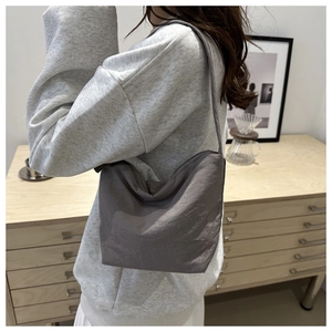 Side view of dark gray nylon bucket bag with pleats shown in a modern home setting