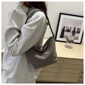 Vue détaillée d'un sac d'épaule demi-lune en toile gris foncé porté par un mannequin