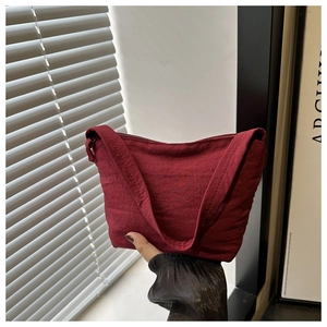 Detail of dark red nylon shoulder bag showing pleated fabric texture and curved zipper