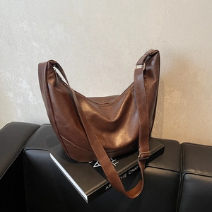 Brown half-moon crossbody bag in textured faux leather with adjustable strap
