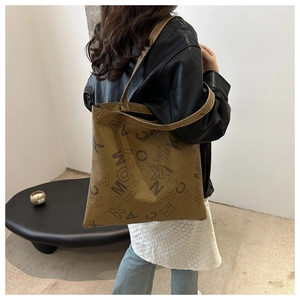 Detail of the large brown tote bag showing the letter print texture and leather material